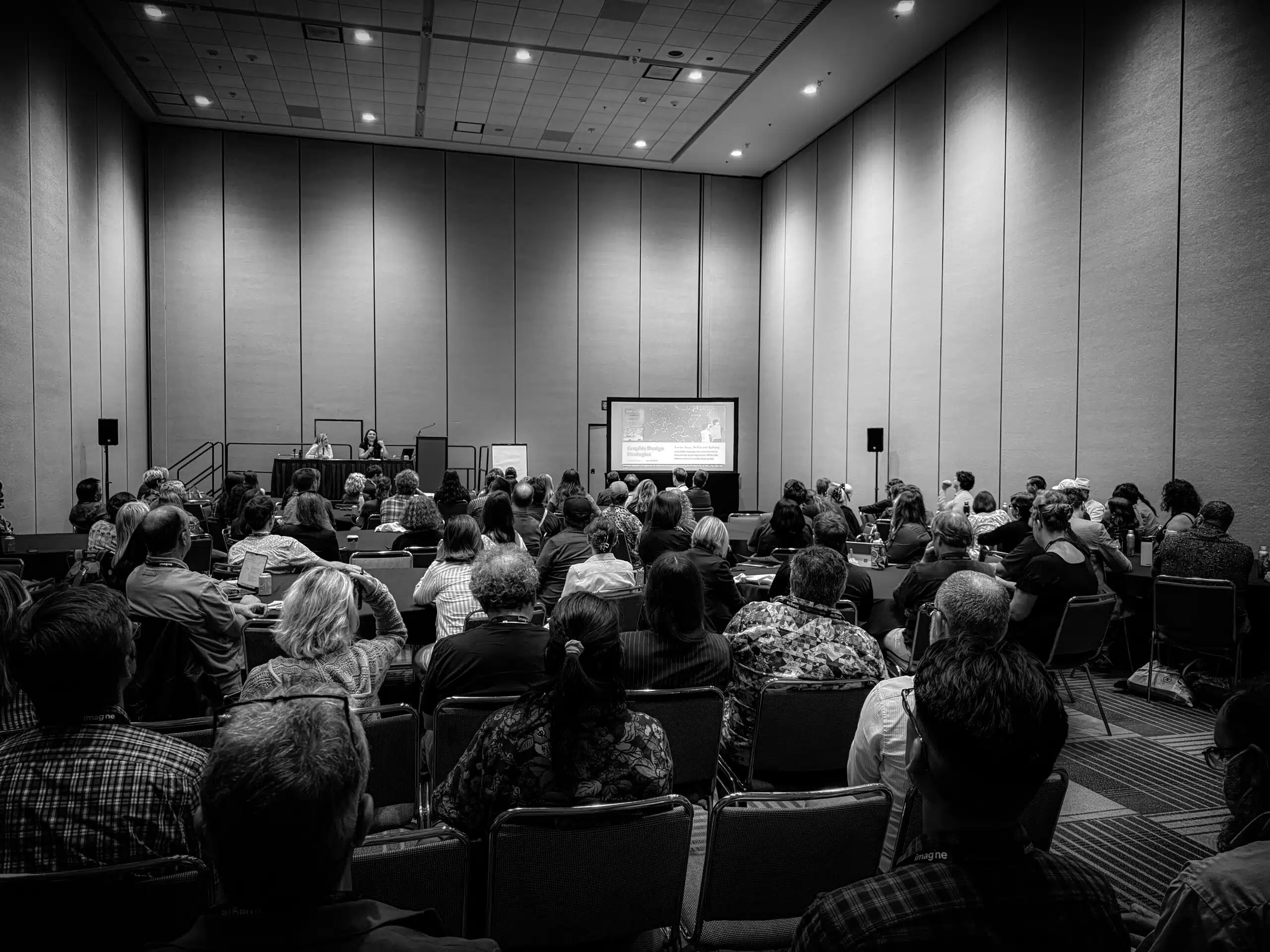 An indoor civic science gathering photographed in monochrome.
