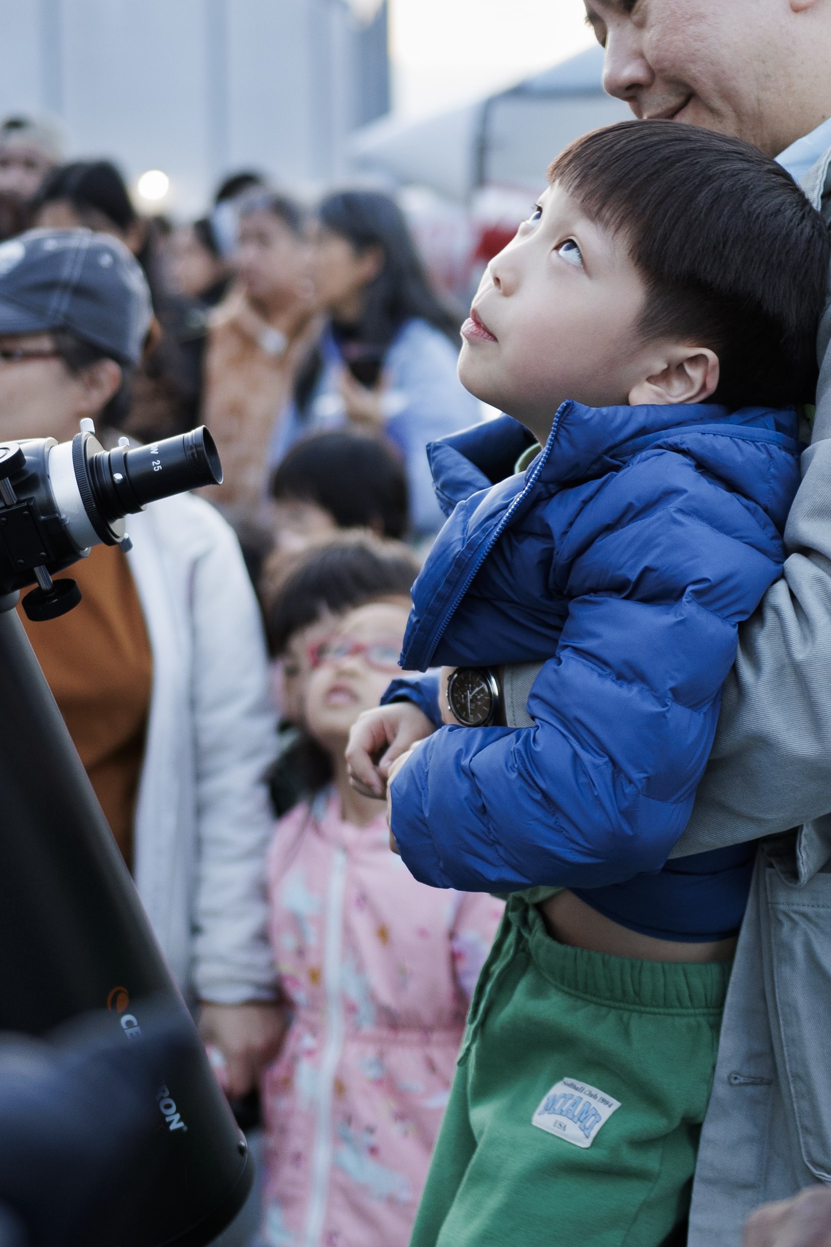 A child looks back up at the moon after seeing it through the telescope.